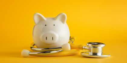 piggy bank with stethescope wrapped around on a yellow background