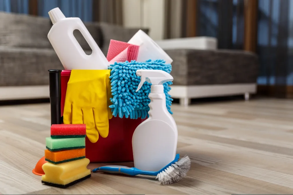 cleaning supplies on floor, yellow gloves, white bottles, stack of sponges, housekeeping