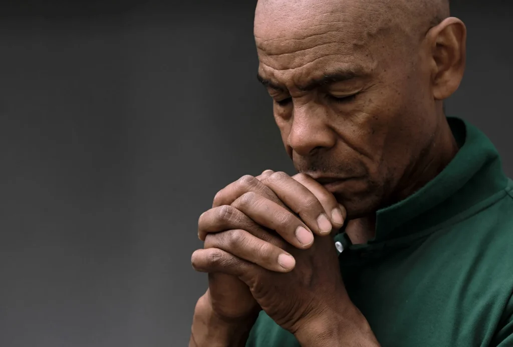 Senior man praying with hands folded, close up