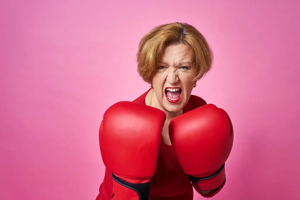 bright pink background, senior woman wearing boxing gloves