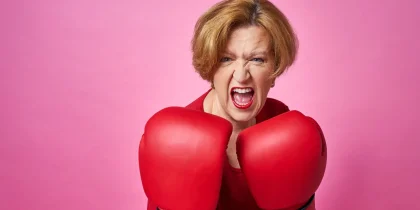 bright pink background, senior woman wearing boxing gloves